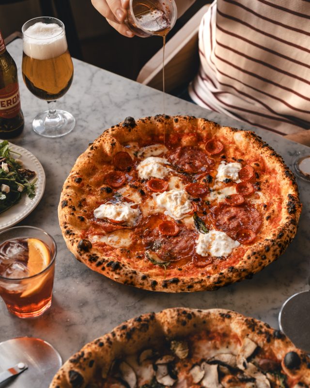 Rudy’s pizzas served alongside fresh salads and refreshing drinks